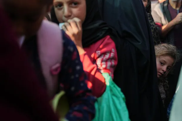 فتاة فلسطينية تقف بين صفوف المنتظرين لتلقي طعام من مطبخ خيري في دير البلح وسط غزة يوم الخميس (أ.ب)