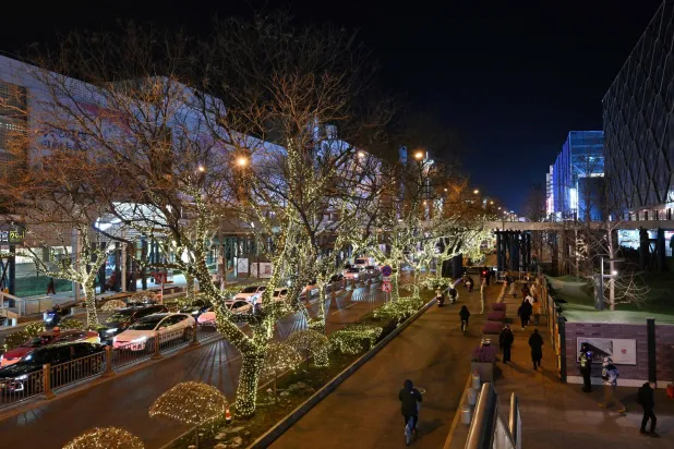 People walk next to shopping centers in Beijing on December 19, 2025. (AFP)