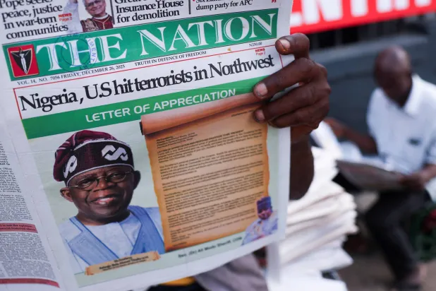 يقرأ الناس الصحف التي تنشر أخباراً عن الغارات الجوية الأميركية على مقاتلي تنظيم «داعش» - لاغوس - نيجيريا - 26 ديسمبر 2025 (رويترز)
