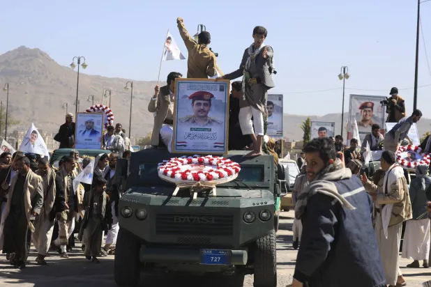 مركبات عسكرية تحمل نعوشاً وصوراً لكبار قادة الحوثيين العسكريين الذين قُتلوا في غارة جوية أميركية (إ.ب.أ)