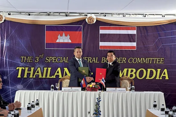 A handout photo made available by the Defense Ministry of Thailand shows Cambodian Defense Minister Tea Seiha (L) and Thai Defense Minister Natthaphon Narkphanit exchanging ceasefire agreement documents during a General Border Committee Meeting in Ban Pak Kard, Chanthaburi Province, Thailand, 27 December 2025. (EPA/Defense Ministry of Thailand/Handout)