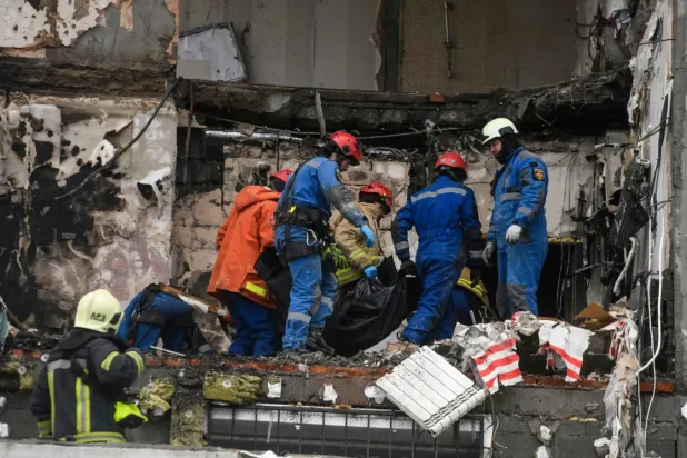 Kurtarma ekibi, 27 Aralık'ta Kiev'e düzenlenen Rus saldırısının kurbanlarından birinin cesedini taşıyor (AFP)