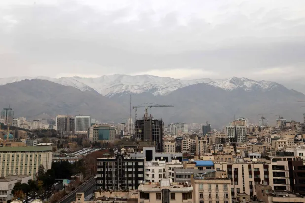 A general view shows the Iranian capital Tehran with the snow-covered Alborz mountain range in the background on December 9, 2025. (Photo by ATTA KENARE / AFP)