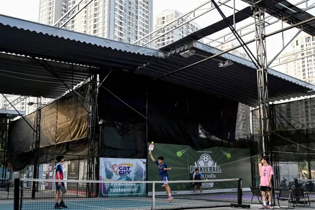 This photo taken on December 23, 2025, shows children playing pickleball in the playground of a residential area in Hanoi. (Photo by Nhac NGUYEN / AFP)
