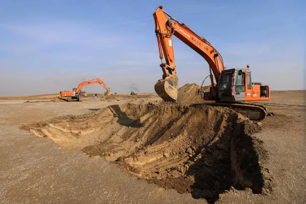 Excavators clear sand dunes and extract clay in the desert south of Samawah on December 21, 2025. (Photo by AHMAD AL-RUBAYE / AFP)
