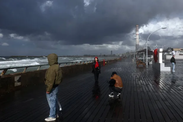 People walk in the rain during stormy weather in the port of Tel Aviv, Israel, 27 December 2025.  EPA/ABIR SULTAN