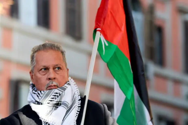 President of the Palestinian Association in Italy, Mohammad Hannoun, carries a Palestinian flag during a nationwide strike, called by the USB union, in solidarity with Gaza and against the government and its plan to increase military spending, in Rome, Italy, November 29, 2025. Italian Interior Minister Matteo Piantedosi said Mohammad Hannoun is among nine people arrested on December 27 on suspicion of financing Hamas through charities based in Italy, in an operation coordinated by anti-mafia and anti-terrorism units. in Italy. REUTERS/Remo Casilli 