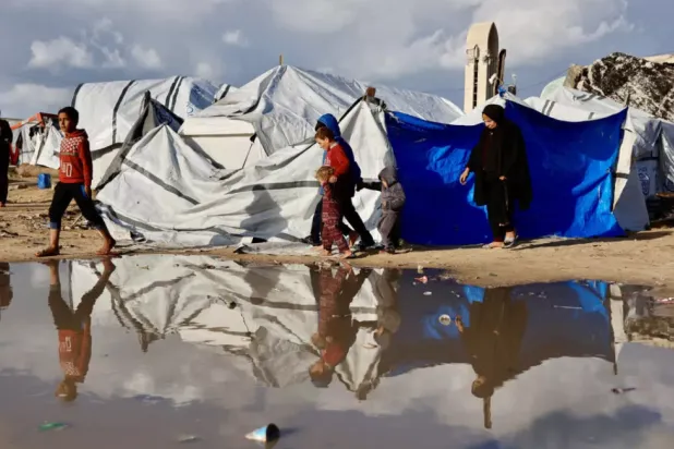 Displaced Palestinians walk past a large pool of standing water in Gaza City. Heavy winter rains have have made an already precarious life worse for displaced Gazans © Omar AL-QATTAA / AFP
