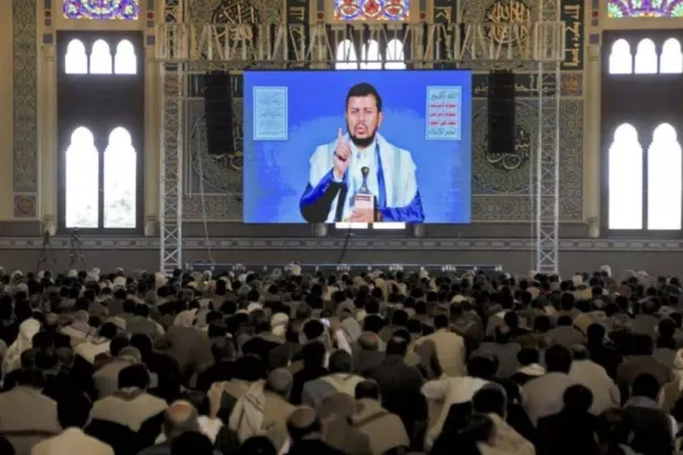 عناصر حوثيون يستمعون إلى زعيمهم عبد الملك الحوثي بقاعة في صنعاء عبر البث التلفزيوني (أ.ف.ب)
