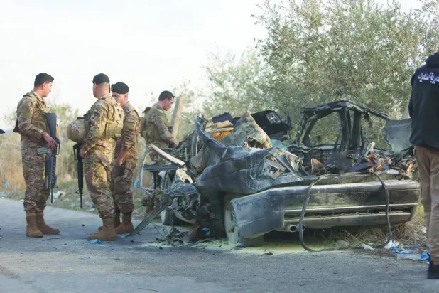 İsrail’in Lübnan'ın güneyindeki Aknit beldesinde hedef aldığı ve üç kişinin hayatını kaybettiği bir aracın yanında duran Lübnan askerleri (DPA)