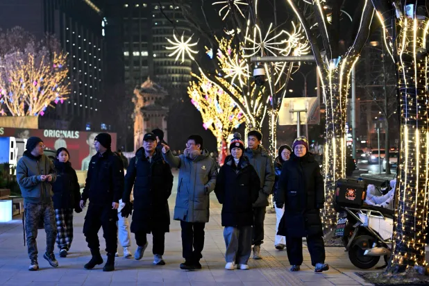 People walk past a shopping mall in Beijing on December 28, 2025. (AFP)