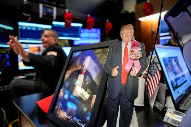 صورة للرئيس الأميركي دونالد ترمب أثناء عمل المتداولين في بورصة نيويورك (رويترز)