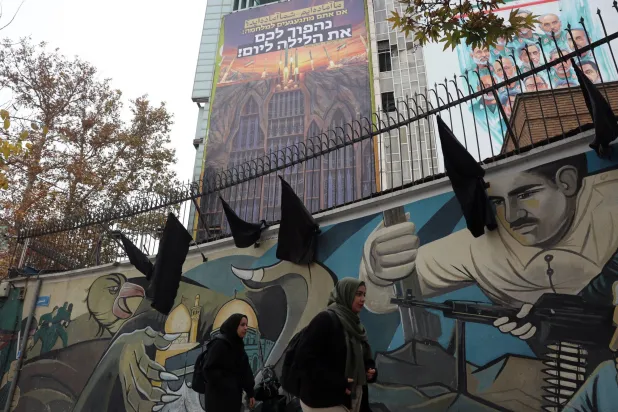 إيرانيتان تمران بجانب لوحة دعائية مناهِضة لإسرائيل تحمل عبارة: «نحن مستعدون... هل أنتم مستعدون؟» معلقة في ساحة وسط طهران (إ.ب.أ)