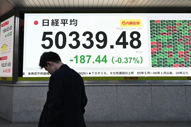 أحد المشاة يمر أمام شاشة إلكترونية تعرض حركة الأسهم في وسط العاصمة اليابانية طوكيو (إ.ب.أ)