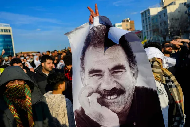(FILES) Supporters display a poster depicting jailed leader of the Kurdistan Workers' Party (PKK) Abdullah Ocalan, after he called on the Kurdistan Workers' Party (PKK) to disarm and dissolve itself in Diyarbakir, southeastern Türkiye, on February 27, 2025. (Photo by Yasin AKGUL / AFP)