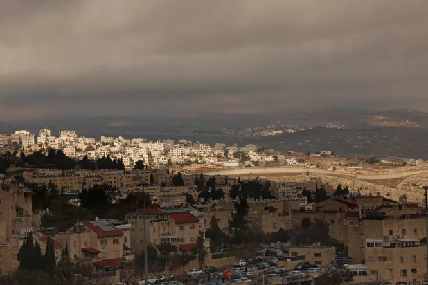 This picture shows the Israeli settlement of Pisgat Zeev, (foreground) in the northern area of East Jerusalem and Israel's controversial barrier separating the Palestinian neighborhood of al-Ram (background) in the occupied West Bank on December 27, 2025 (AFP)