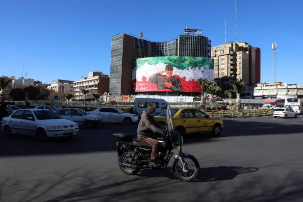 Iranians drive past a huge banner of former Iranian Revolutionary Guard Corps (IRGC) Quds Force commander Qassem Soleimani ahead of the sixth anniversary of his assassination at Valiasr Square in Tehran, Iran, 30 December 2025. (EPA)