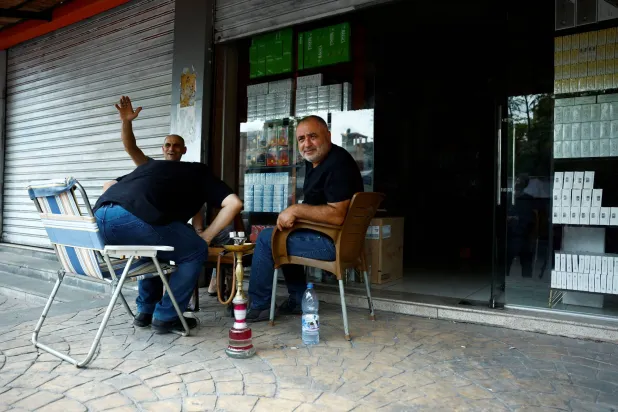 رجال يدخنون الشيشة خارج محل لبيع تبغ في ريف اللاذقية 25 سبتمبر (رويترز)