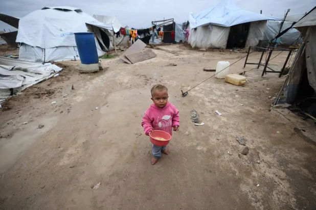 طفل يقف وسط ملاجئ مؤقتة للنازحين الفلسطينيين في مخيم البريج للاجئين وسط قطاع غزة (أ.ف.ب)