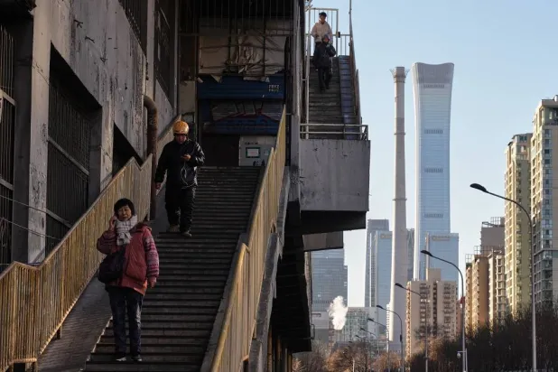 People walk down steps near a residential building area with a view of China Zun, the tallest skyscraper in Beijing, Tuesday, Dec. 23, 2025. (AP)
