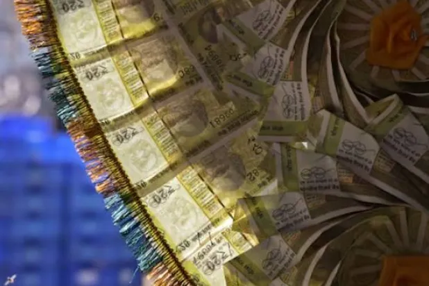 عقد من العملات الهندية معروض عند كاونتر صرف الأموال في الأحياء القديمة بدلهي (رويترز)
