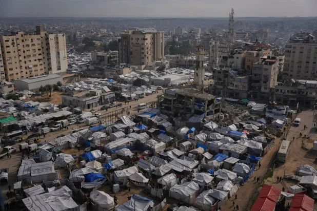 فلسطينيون يسيرون في شوارع مدينة غزة مروراً بمخيمات النازحين (أ.ب)