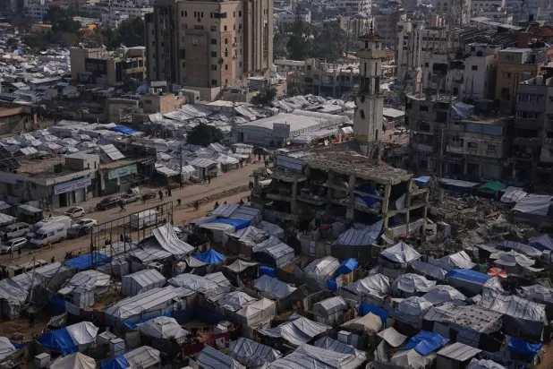 Palestinians walk along streets past tent camps for displaced people in Gaza City, Wednesday, Dec. 31, 2025. (AP)