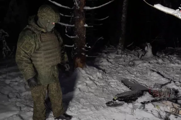 A Russian service member stands next to the remains of a drone, which, according to the Russian Defense Ministry, was downed during the repelling of an alleged Ukrainian attack on the Russian presidential residence in the Novgorod Region, in an unknown location in Russia, in this still image from a video released December 31, 2025. (Russian Defense Ministry/Handout via Reuters)