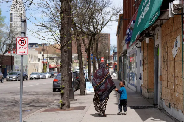  سيدة وطفلها في أحد الأحياء التي تقطنها الجالية الصومالية في مينيابوليس مايو 2022 (أ.ب)