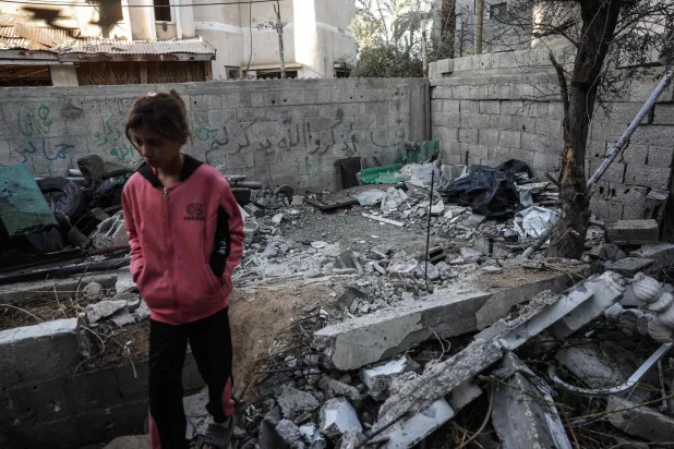 A young girl walks through the site of an Israeli airstrike in Deir al-Balah on December 9, 2025, which resulted in a Palestinian man being killed. (Photo by BASHAR TALEB / AFP)