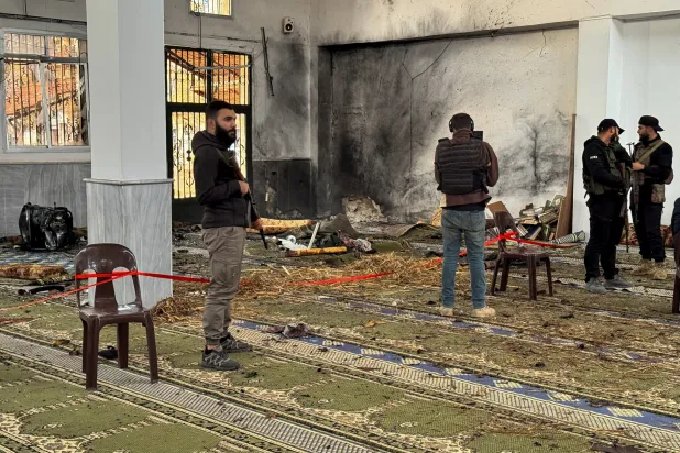 Syrian security forces stand inside a damaged mosque after several people were killed in an explosion at a mosque as the Syrian Arab News Agency (SANA) said, in Homs, Syria December 26, 2025. REUTERS/Ali Ahmed al-Najjar 