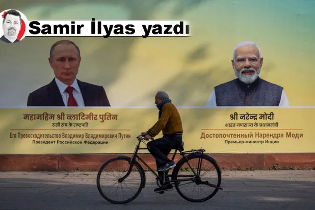 Yeni Delhi'de Hindistan Başbakanı Narendra Modi ve Rusya Devlet Başkanı Vladimir Putin'in fotoğraflarının önünde bisiklet süren bir adam, 4 Aralık 2025 (Reuters)