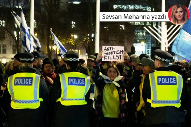 Londra'daki İngiltere Parlamentosu önünde düzenlenen protesto gösterisinde antisemitizmin reddedildiği bir pankartı tutan bir kadın (AFP)