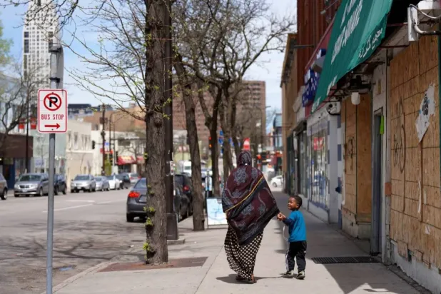 A woman and a child hold hands as they walk down a street in the predominantly Somali neighborhood of Cedar-Riverside in Minneapolis in May 2022. Jessie Wardarski/AP