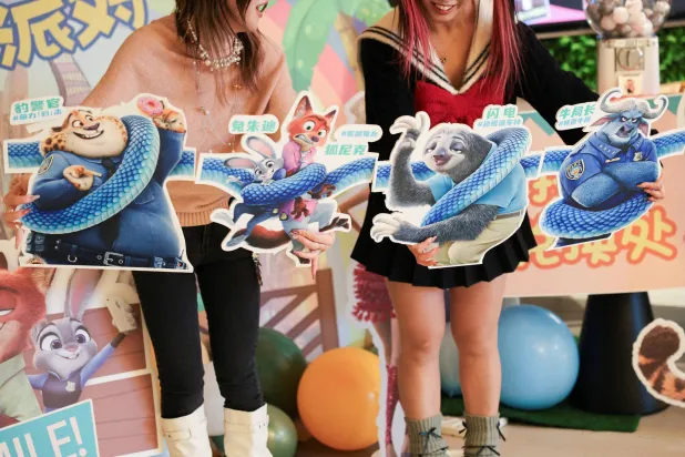 FILE PHOTO: Moviegoers hold character cutouts to pose for a photo at a movie theater on the release day of the movie Zootopia 2, in Shanghai, China, November 26, 2025. REUTERS/Go Nakamura/File Photo