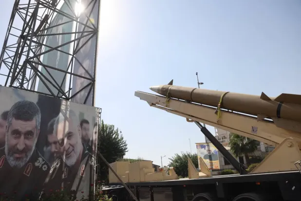 Tahran'ın merkezindeki bir sokakta, İran'a ait bir balistik füze, Devrim Muhafızları'nın eski dış operasyonlar başkanı Kasım Süleymani ve geçen haziran ayında İsrail saldırısında öldürülen füze programı başkanı Emir Ali Hacızade'nin resimlerinin bulunduğu bir pankartın yanında sergileniyor (Reuters)