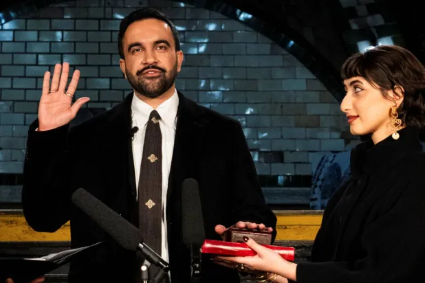 ممداني لدى أدائه القسم على نسخة من المصحف حملتها زوجته في نيويورك أمس (رويترز)