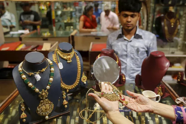 متسوقة تحمل قلادة ذهبية في متجر مجوهرات في مومباي بالهند (رويترز)
