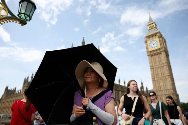 FILE PHOTO: A woman shields herself from sun with an umbrella at Westminster Bridge in London, Britain, June 21, 2025. REUTERS/Isabel Infantes/File Photo