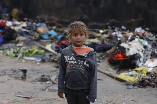 A young girl stands in front of tents that burned after candles were lit for lighting at a displacement camp in Gaza City on Friday (AFP)