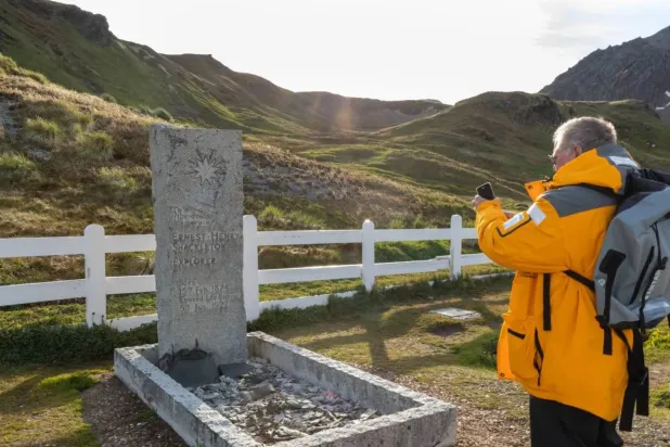 A person taking a photo of Ernest Shackleton's grave, polar explorer, who died after a heart attach in 1922 (Shutterstock)