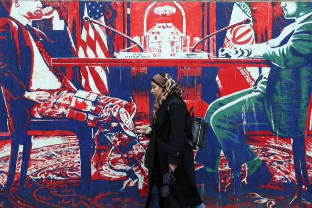 An Iranian woman walks past an anti-US mural on a street in Tehran, Iran, 03 January 2026. EPA/ABEDIN TAHERKENAREH