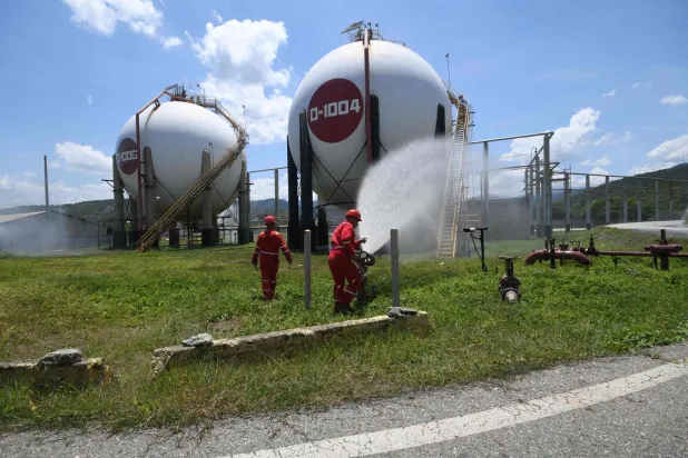 عمال شركة النفط الوطنية الفنزويلية يشاركون في تدريب للحد من مخاطر الكوارث الطبيعية والنزاعات المسلحة بمصفاة «إل باليتو» في بويرتو كابيلو (أ.ف.ب)