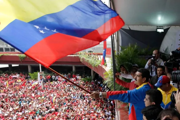 Venezuela's acting President Nicolas Maduro waves a national flag over supporters after registering his candidacy for president to replace late President Hugo Chavez at the national electoral council in Caracas, Venezuela, March 11, 2013. (AP Photo/Ariana Cubillos, File) 