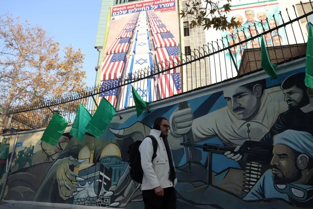 لوحة دعائية مناهضة للولايات المتحدة وإسرائيل في ميدان فلسطين وسط طهران تحمل رسالة من أمين المجلس الأعلى للأمن القومي علي لاريجاني كُتب فيها: «انتبهوا لجنودكم»، ردّاً على دعم الرئيس الأميركي دونالد ترمب للاحتجاجات المناهضة للحكومة (إ.ب.أ)