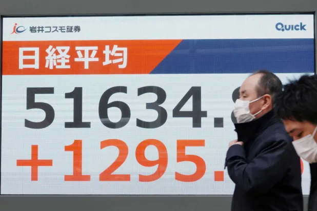يمر المشاة أمام لوحة إلكترونية تعرض أرقام مؤشر «نيكي» في بورصة طوكيو (أ.ف.ب)