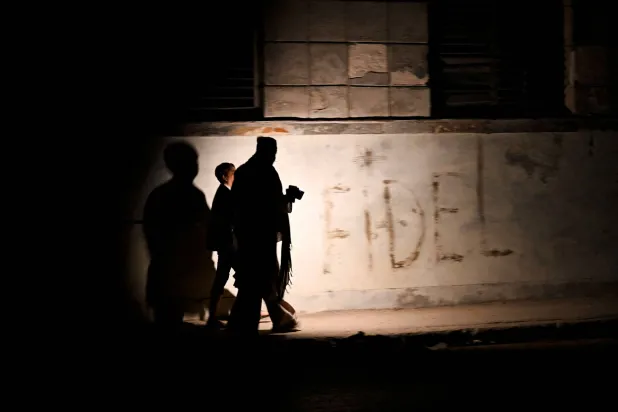 Cubans walk on a street during a general blackout in Havana on March 14, 2025. (Photo by YAMIL LAGE / AFP)