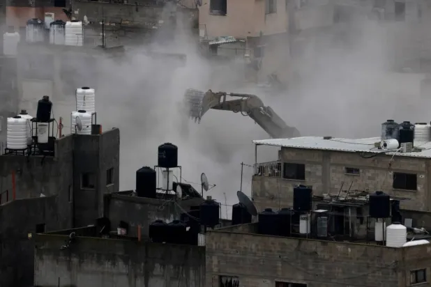 An Israeli army excavator demolishes buildings during a military operation in Nur Shams refugee camp, near the West Bank city of Tulkarem, 31 December 2025. (EPA) 