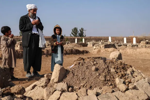 Gul Ahmad (center) along with his deceased stepbrother Habibullah's son Waheed (right) and Saeed offering prayers over his grave in Ghunjan. Mohsen KARIMI / AFP
