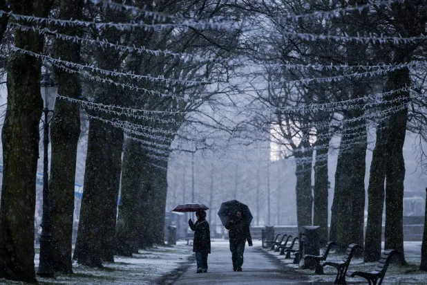 People walk through a winter shower with umbrellas in Amsterdam, the Netherlands, 04 January 2026. (EPA) 